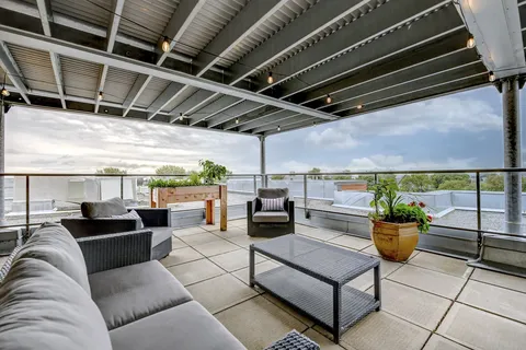 Covered terrace with sofas, chairs and potted plants