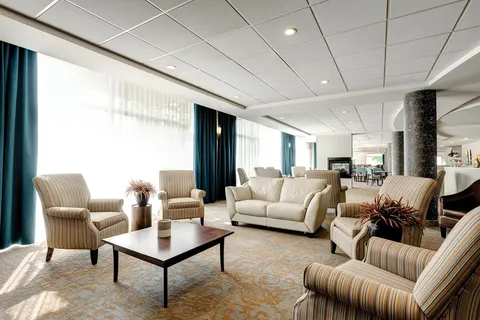 Sitting area with a sofa, striped armchairs and large windows