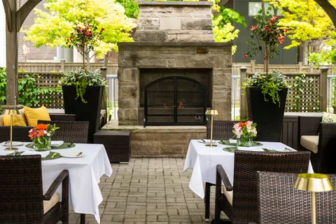 Outdoor dining tables beside a stone fireplace.