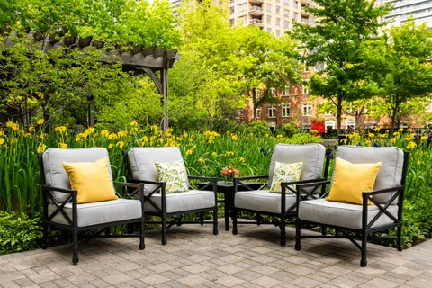 Garden patio with four armchairs and flowering plants.