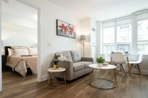 Suite sitting area with a sofa, tables and an adjoining bedroom.
