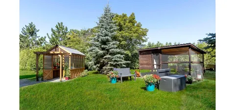 Garden with two wooden shelters, benches, lawn and flowering plants