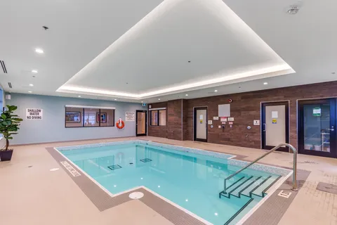 Indoor pool with handrails and a tiled deck