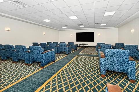Theatre room with rows of reclining chairs facing a blank screen
