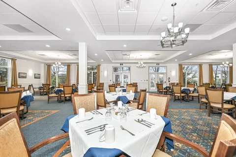 Dining room with set tables, upholstered chairs and large windows