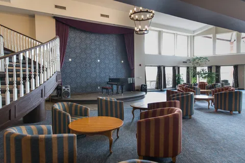 Central gathering area with tables, chairs, a piano and a stage.