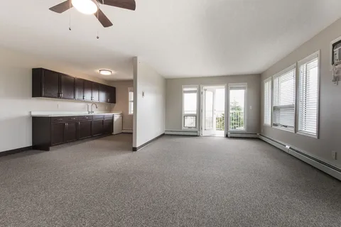 Unfurnished suite with a kitchenette and balcony doors.