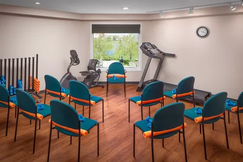 Exercise room with chairs, weights, a treadmill and a stationary bicycle