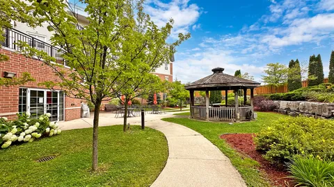 Garden path through lawns and planting beside a wooden gazebo