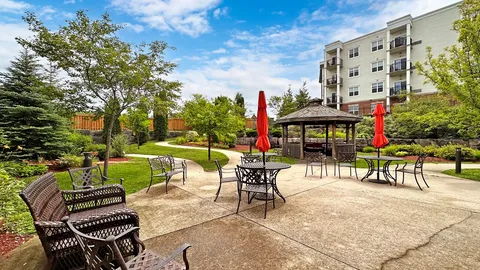 Garden patio with tables, chairs, red umbrellas and a gazebo