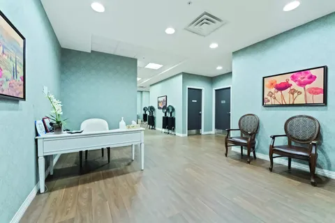 Salon reception area with chairs, a desk and hood dryers