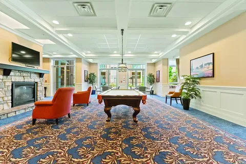 Room with a pool table, red armchairs and a fireplace