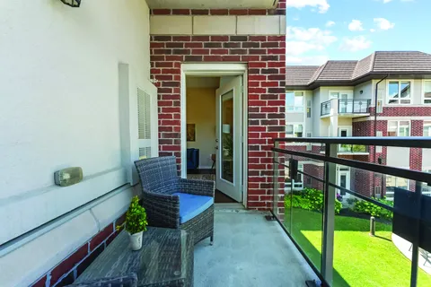Balcony with a wicker chair beside brick walls