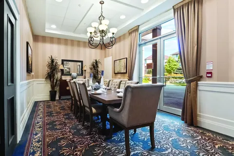 Dining table with upholstered chairs beside tall windows