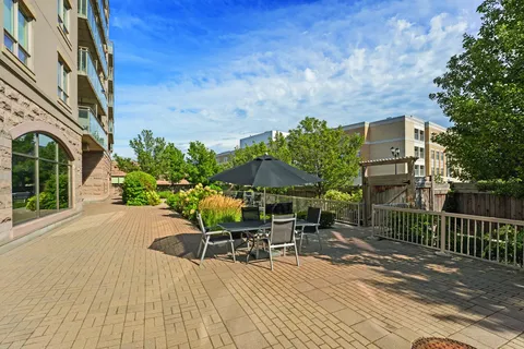 Paved patio with a table, chairs and a black umbrella