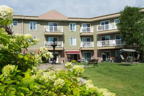 Garden with a fountain, bench, swing seat and lawn beside residence balconies