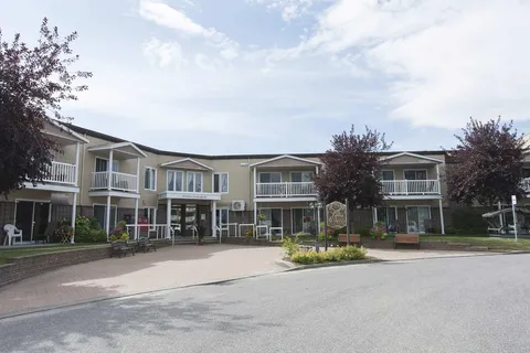Residence building with balconies around a paved forecourt and flower beds