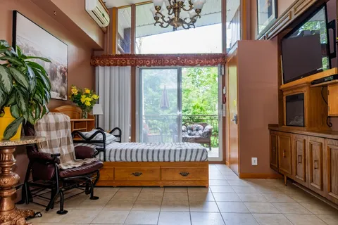 Sunroom with wooden chairs, window seat and television.