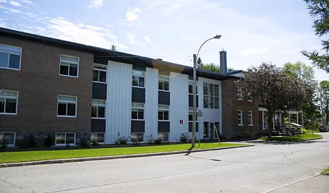 Three-storey brick residence with white cladding, a lawn and a street in front