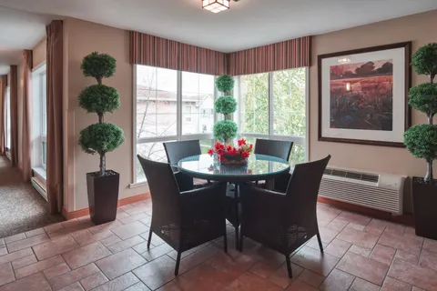 Round table and chairs beside corner windows