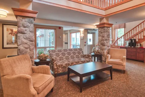 Lobby seating beside stone columns and a wooden staircase