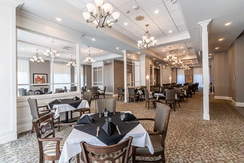 Dining room with chandeliers, wooden chairs and tables set with black and white linens