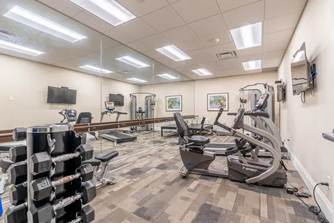 Exercise room with weights, cardio machines and a mirrored wall