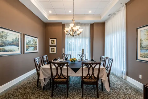 Dining room with a rectangular table, wooden chairs and landscape pictures