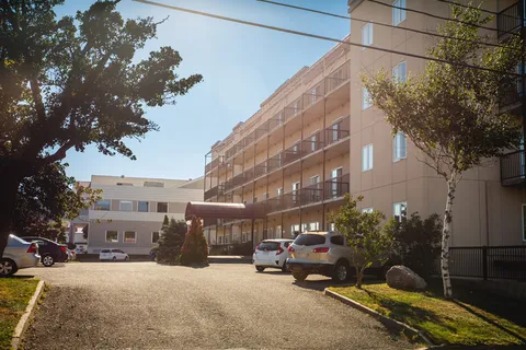 Residence with balconies, a covered entrance and cars parked in front