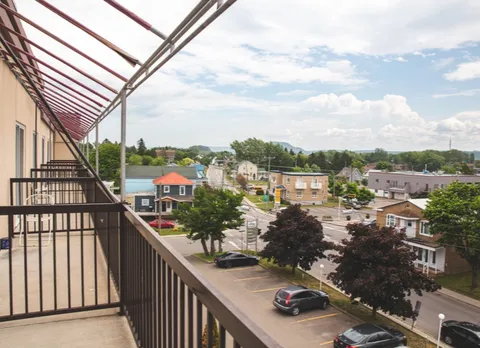 Balcony railing and awning overlooking trees, parked cars and nearby streets