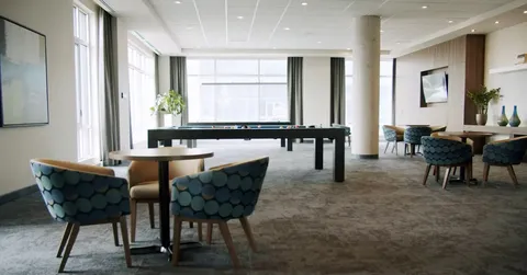 Billiard table and chairs beside large windows