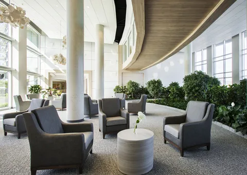 Glazed atrium with armchairs and a planted indoor garden
