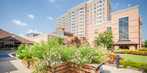 Brick residence building behind a flower bed, paved walkways and a gazebo
