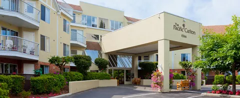 Cream building with balconies, covered entrance and flowering planters