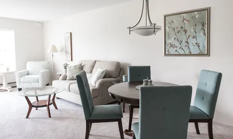 Sitting and dining area with a sofa, armchairs, a round table and floral wall art