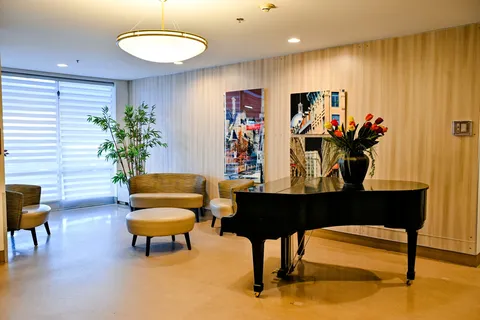 Grand piano and chairs beside a wood-panelled wall and potted plants