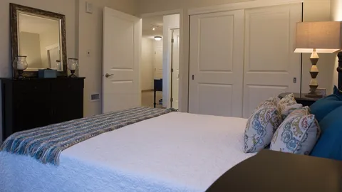 Suite bedroom with a bed, dresser and doors to adjoining rooms.