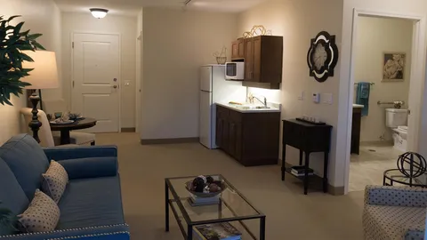 Suite living area with a sofa, kitchenette and a bathroom doorway.