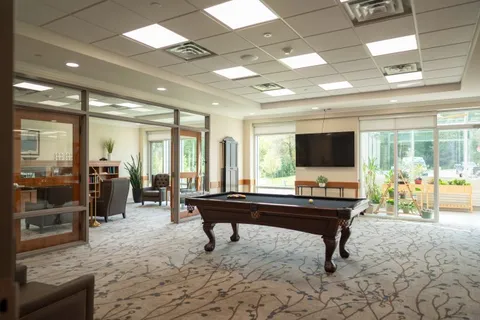 Room with a pool table, a television and glass doors