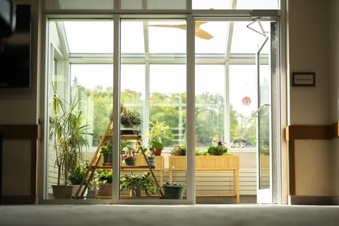 Room with large windows, raised planters and potted plants