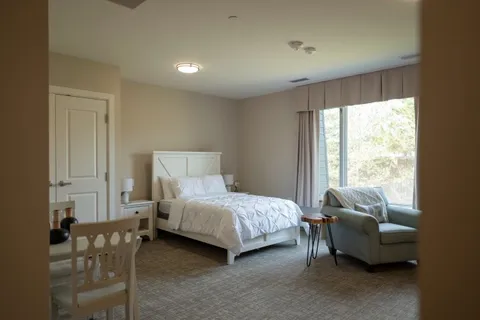 Bedroom with a bed, armchair, dining table and window