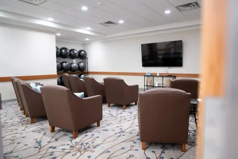 Room with armchairs facing a television beside exercise balls