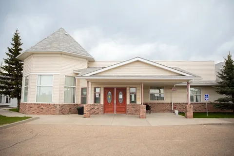 Aspen House entrance with red doors, a covered porch and a peaked tower.