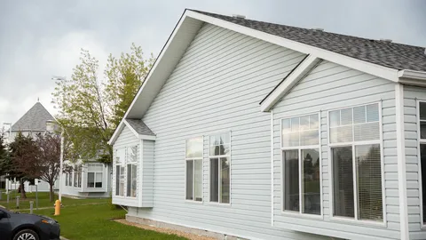 White-sided building wing with large windows beside the lawn.
