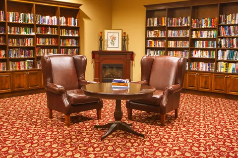 Library with bookshelves, armchairs and a fireplace