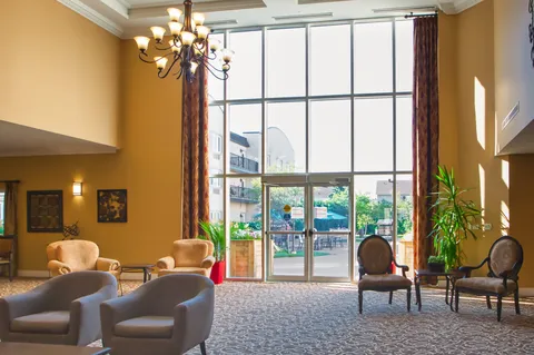 Lobby seating beneath a chandelier beside tall entrance windows