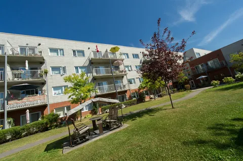 Lawn, garden beds and a covered swing beside the residence's balconies