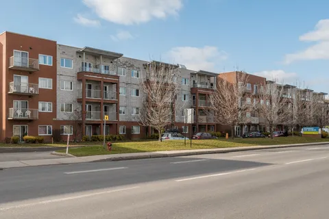Four-storey residence with balconies beside a road and parked cars