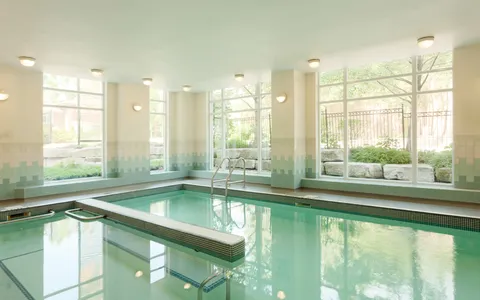 Indoor pool with large windows and metal entry rails.