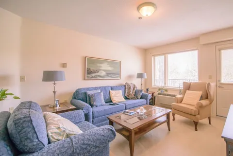 Room with a blue floral sofa, two armchairs, a glass coffee table and a window
